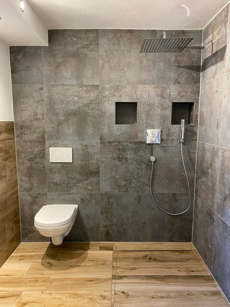 Dusche mit grauen Fliesen und Boden in Holzoptik