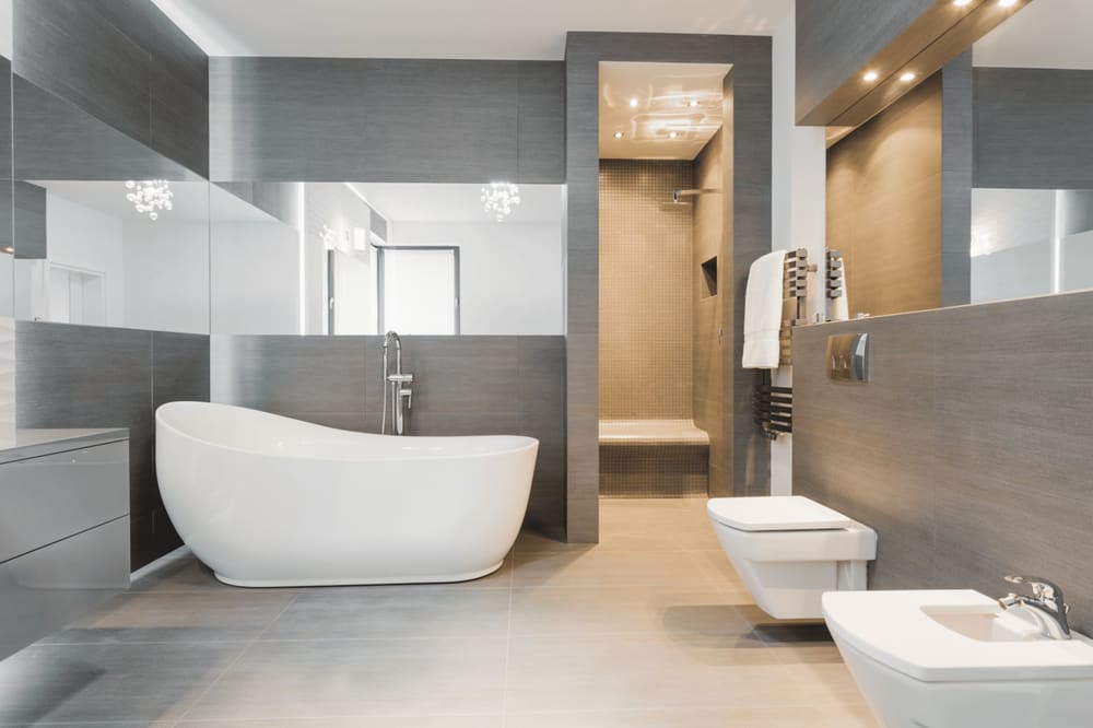 Bad mit freistehender Badewanne, grauen Fliesen und Dusche